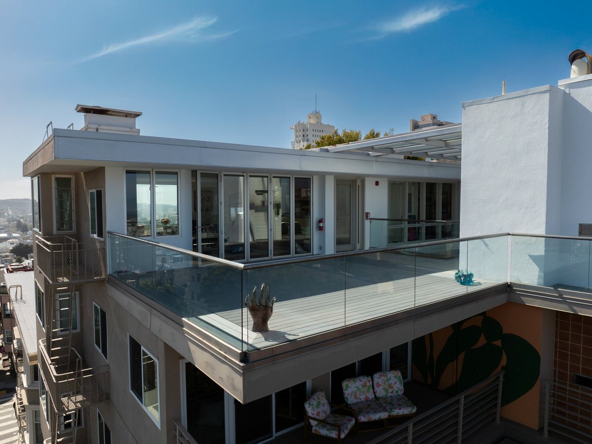 Rooftop deck with frameless glass railing and composite decking above the San Francisco skyline