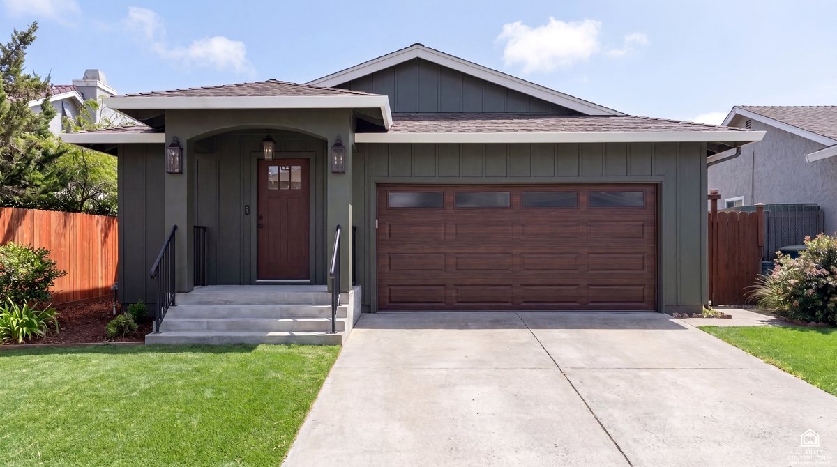 Single story home in board and batten siding with a new roof, porch and painted trim