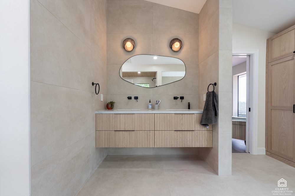 Floating fluted oak vanity with a stone top, round mirror and wall sconces