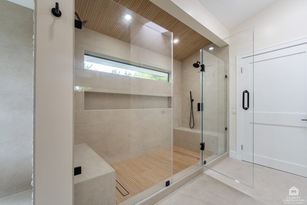 Curbless walk in shower with a clerestory window, teak seat and a stone bench