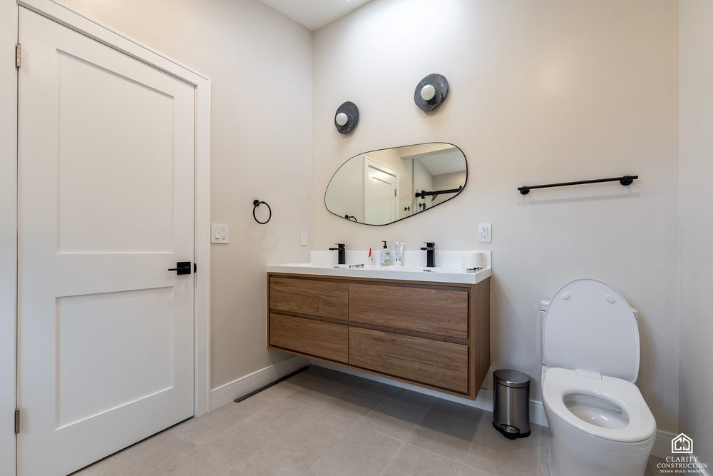 Guest bathroom with a floating walnut vanity, round mirror and black fittings