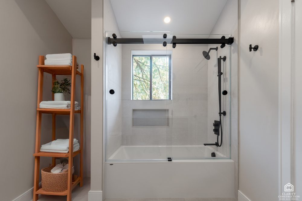 Tub and shower with black rail hardware, a tiled niche and a window to the garden