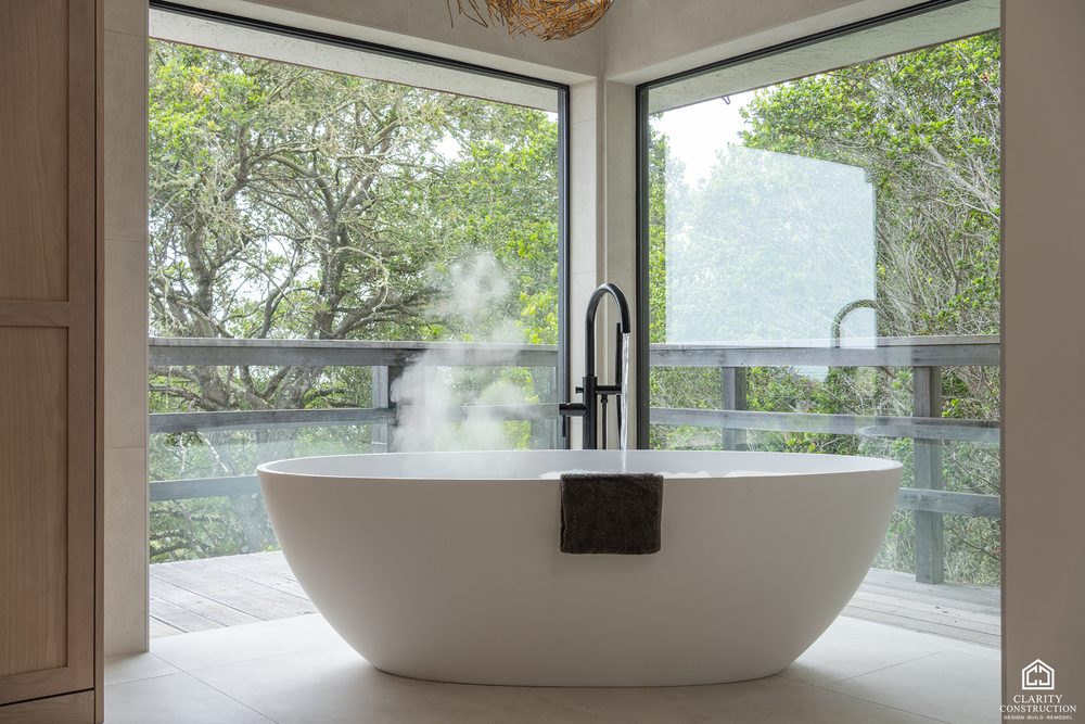 Corner window bathroom with a freestanding tub and a black floor mounted tub filler