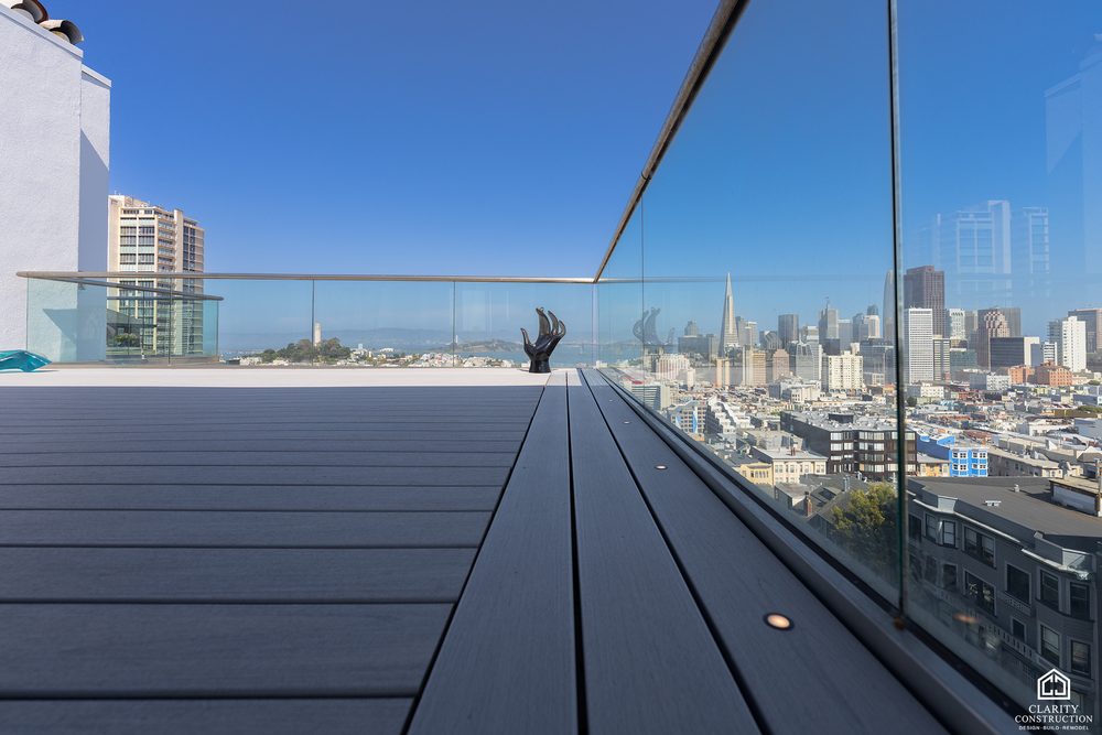 Glass railing along a rooftop deck with the downtown San Francisco skyline beyond