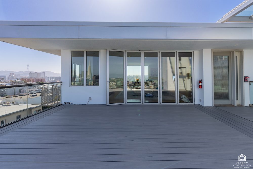 Penthouse folding glass wall opening onto a rooftop deck under a steel pergola