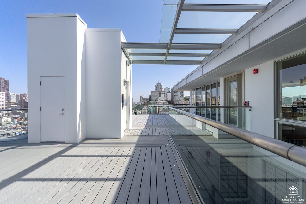 Rooftop walkway in composite decking beside a rendered stair core and glass balustrade