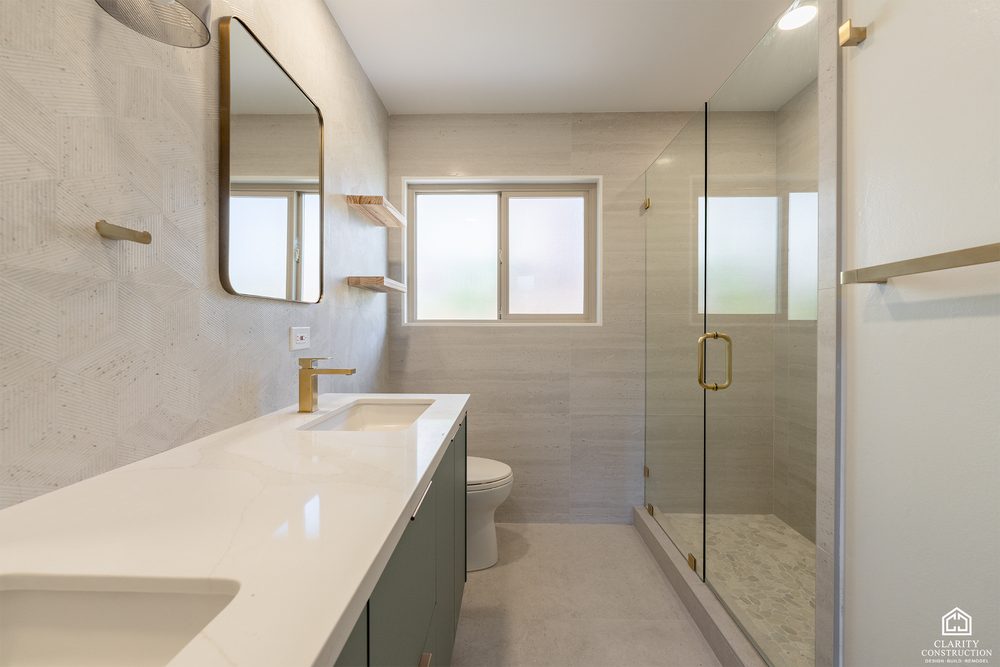 Bathroom with a sage green vanity, brass fittings and a frameless glass shower
