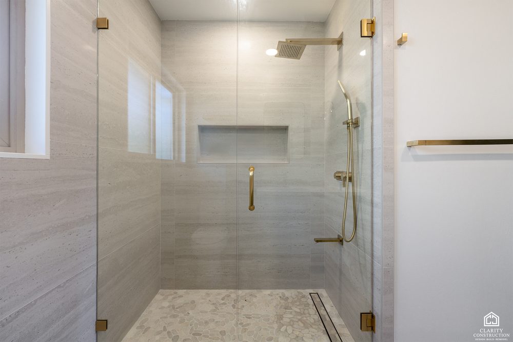 Walk in shower with a full width niche, brass rain head and a linear drain