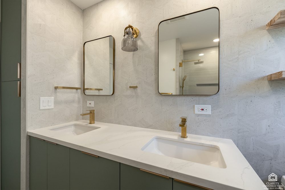 Sage green vanity with a brass faucet, arched mirror and oak shelving