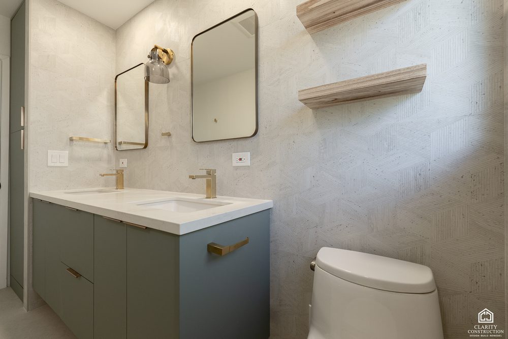 Sage green floating vanity with an integrated stone basin and a brass wall faucet