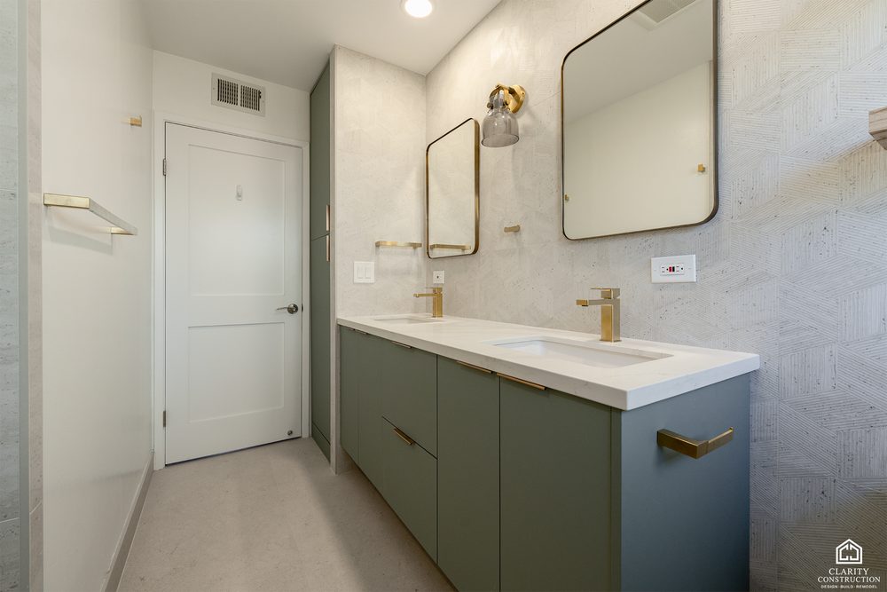 Sage green vanity with a stone integrated basin, brass faucet and floating oak shelf