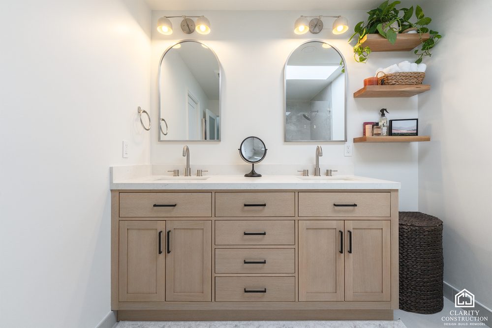 White oak double vanity with arched mirrors, open shelving and brushed black faucets