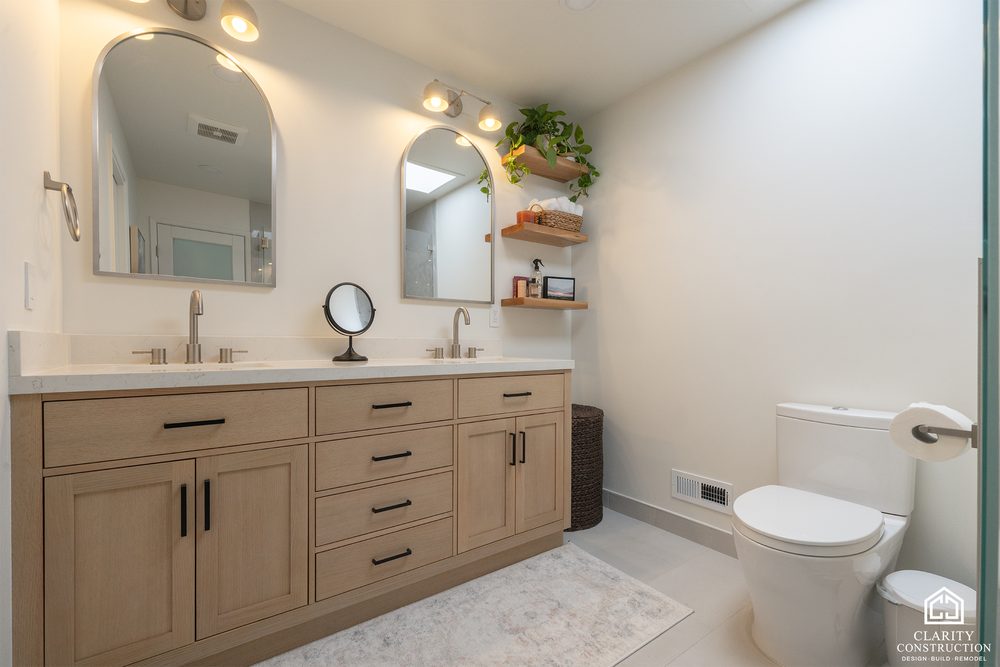 White oak double vanity with arched mirrors seen from the doorway of a remodeled bathroom