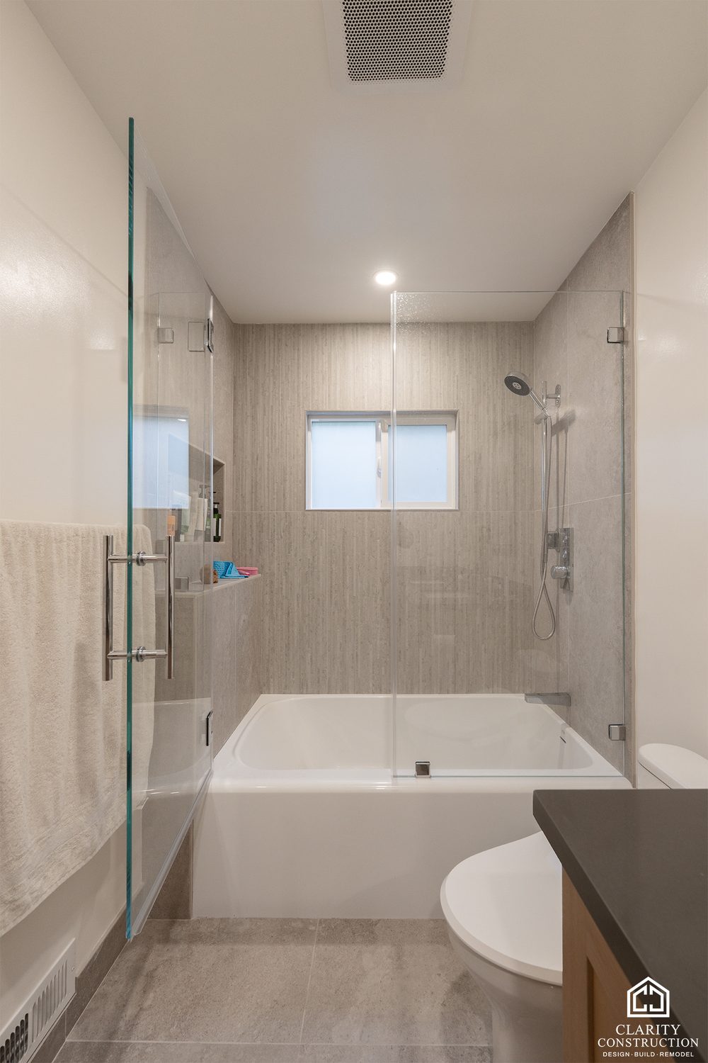 Tub and shower combination in large format tile with a glass screen and a corner window