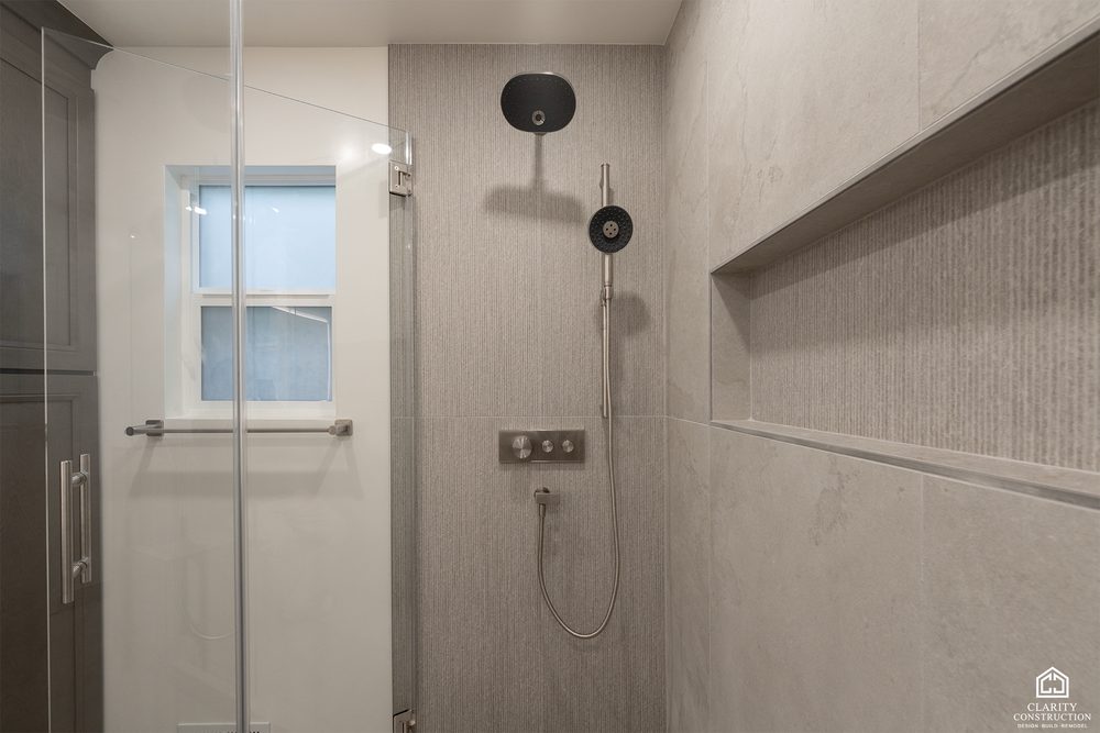 Walk in shower with a full width stone ledge, matte black fittings and a rain head
