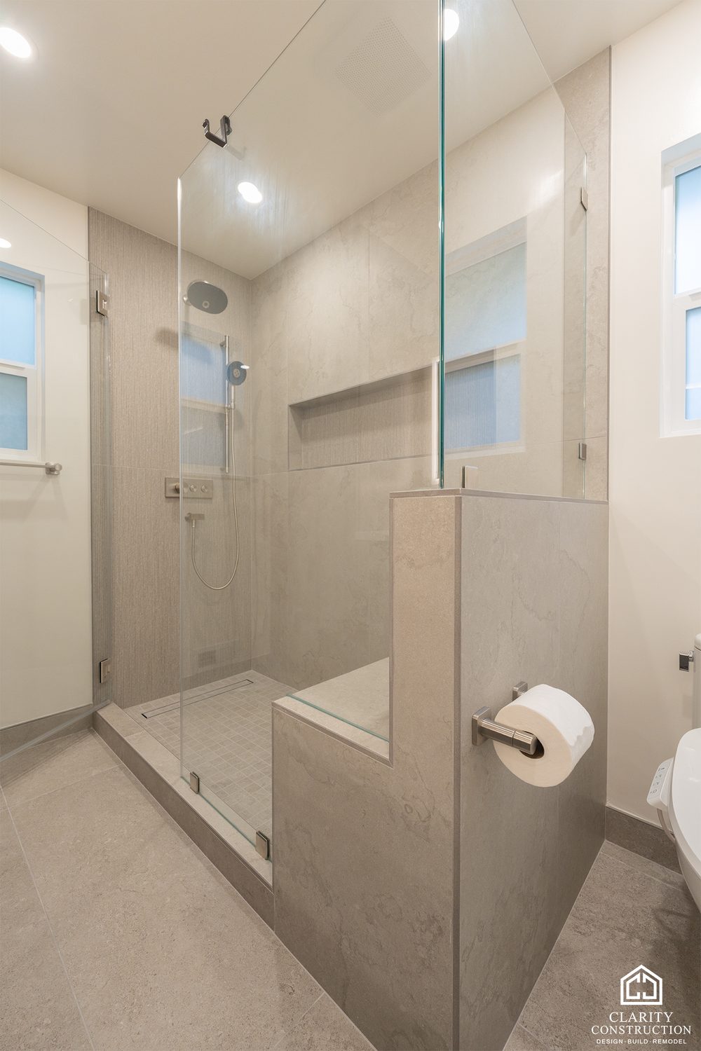 Walk in shower with a tiled bench, glass screen and a window at head height