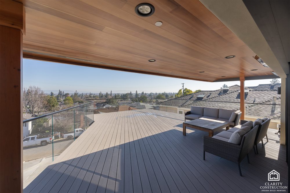 Composite deck under a cedar soffit with frameless glass railing and outdoor seating