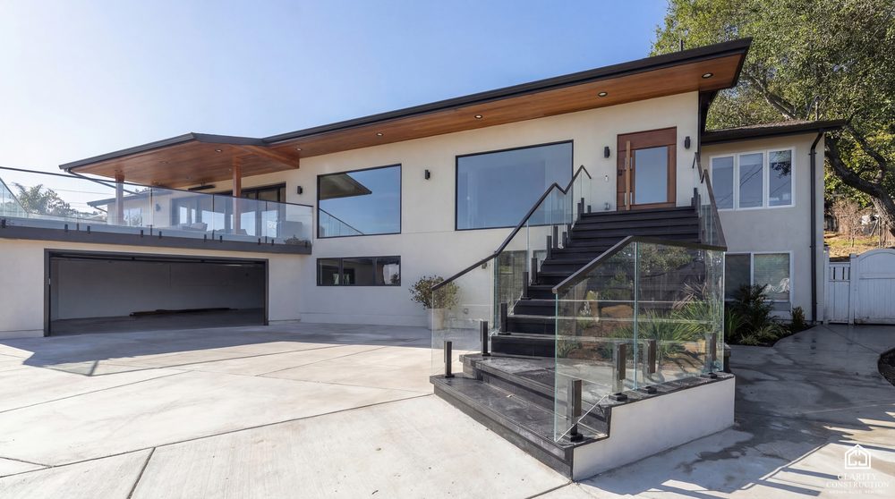 New hillside home with deep eaves, a cedar soffit and a glass railed entry stair