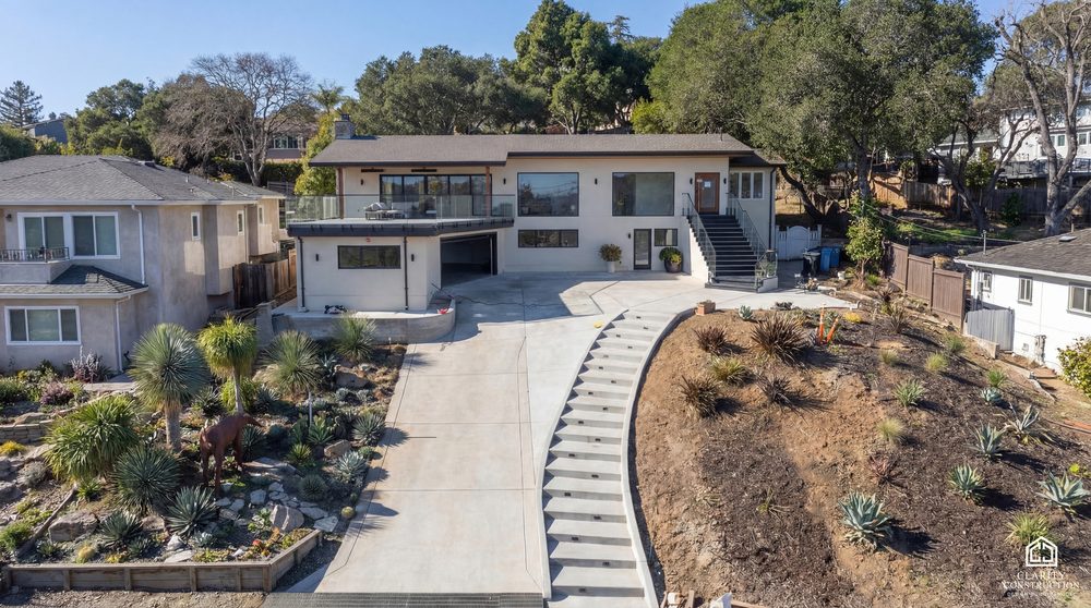 New home on a hillside lot with a poured driveway, terraced planting and a stepped path
