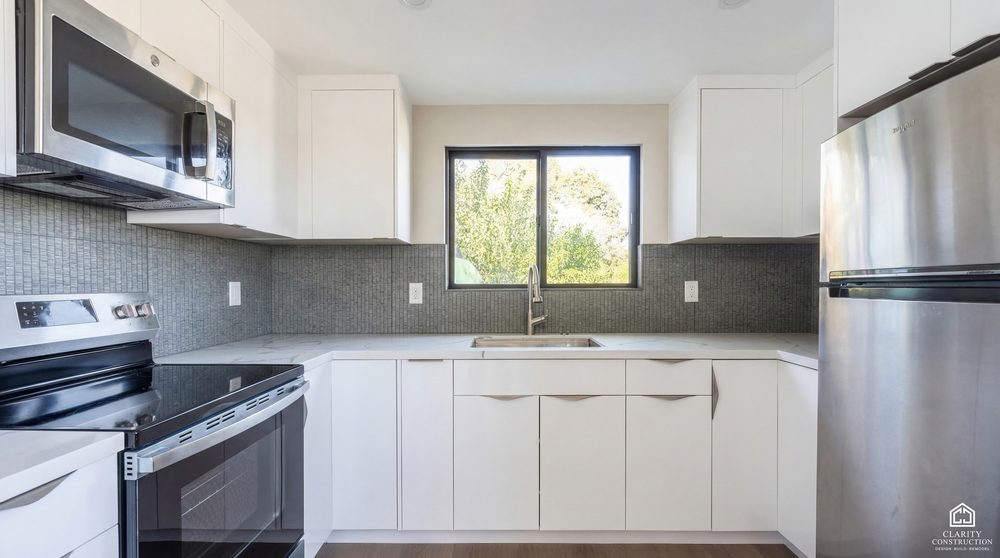 Compact kitchen with white cabinets, a tiled backsplash and stainless appliances