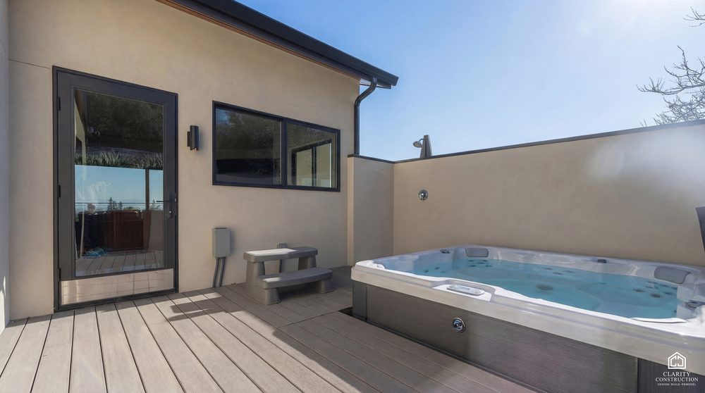 Sunken spa on a composite deck against a rendered privacy wall