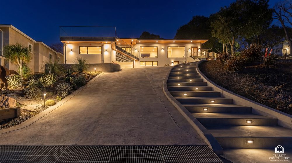 New home at dusk with a lit driveway, stepped path lighting and glowing eaves