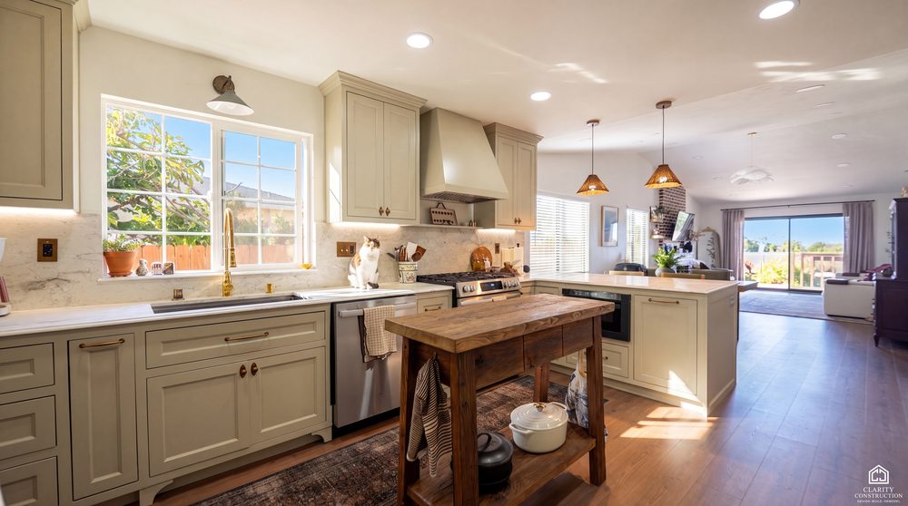 Sage green kitchen with a butcher block island opening onto a living room with wood floors