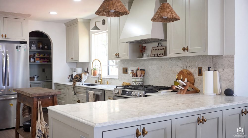 Sage kitchen with a plastered range hood, marble counters and an arched pantry doorway