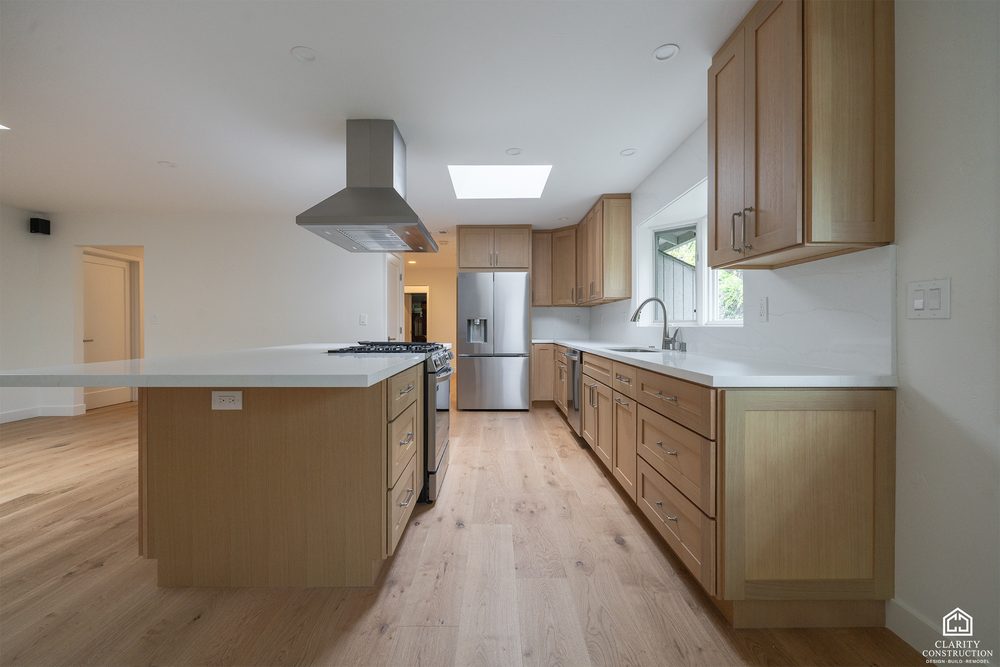 White oak kitchen with a long island, stainless hood and a skylight over the run