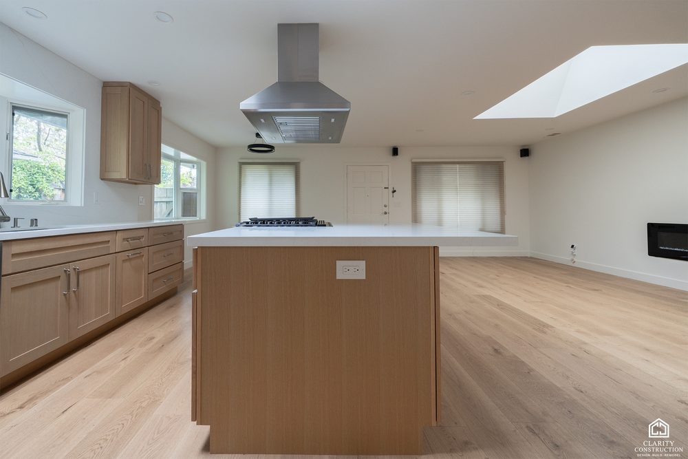 White oak kitchen island under a skylight in an open plan renovated house