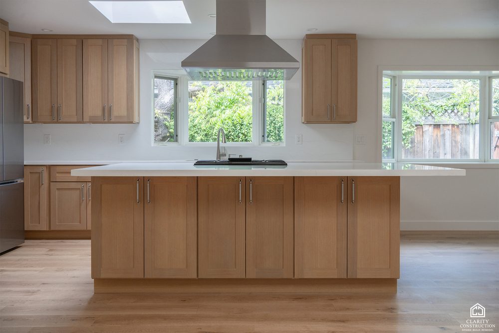 White oak kitchen with a wide island, integrated hood and windows to the garden
