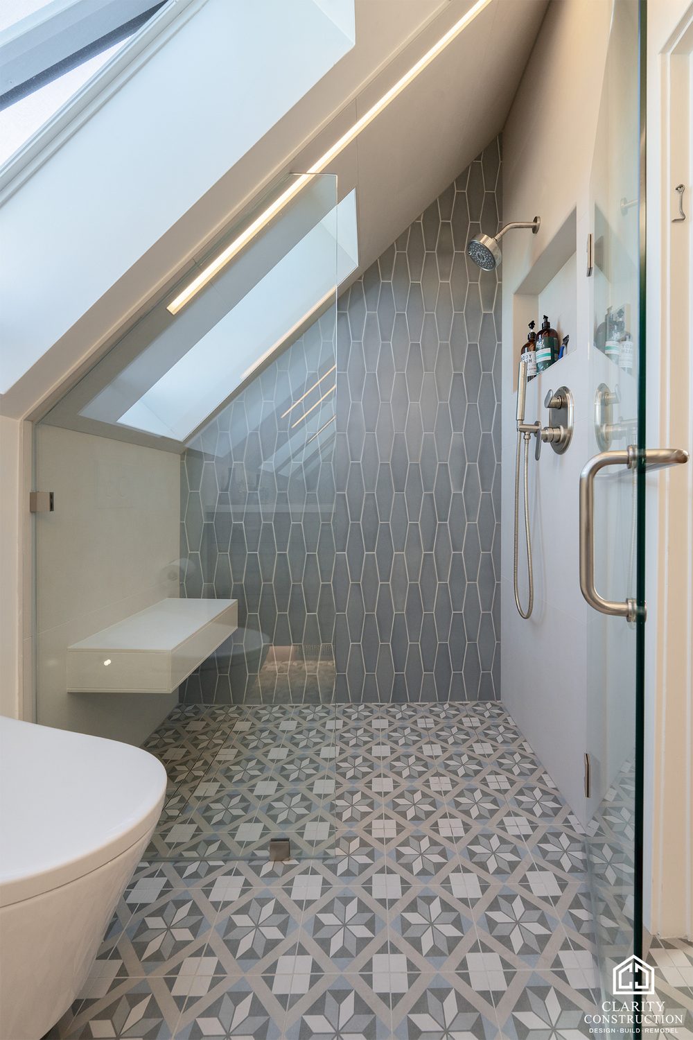 Attic bathroom under a sloped ceiling with a freestanding tub and patterned floor tile