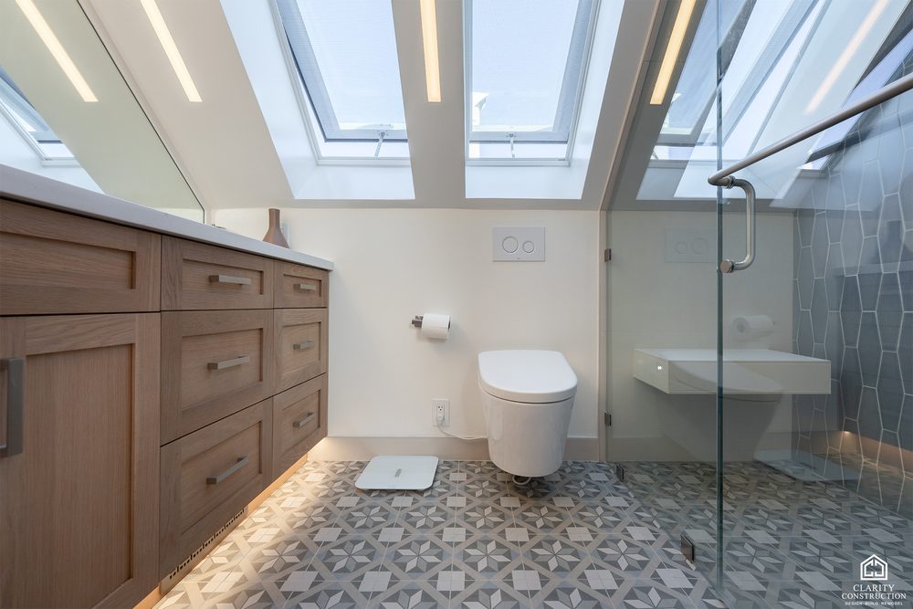 Attic bathroom with an oak double vanity, wall hung toilet and skylights over the shower