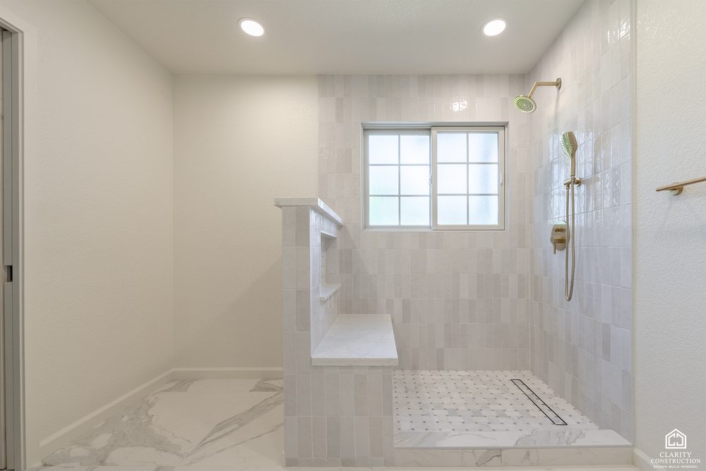 Curbless walk in shower with a built in bench, marble tile and a linear drain