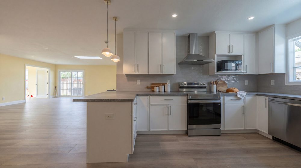 White kitchen with a peninsula, stainless range and a window over the sink