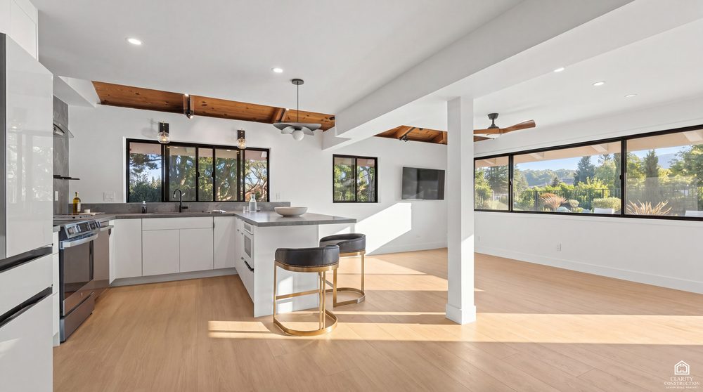 Open plan white kitchen under a cedar beamed ceiling, opening to a living space