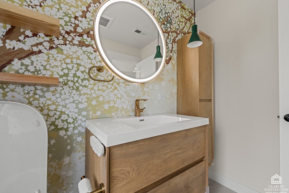 Round backlit mirror over an oak vanity against a hand painted blossom mural