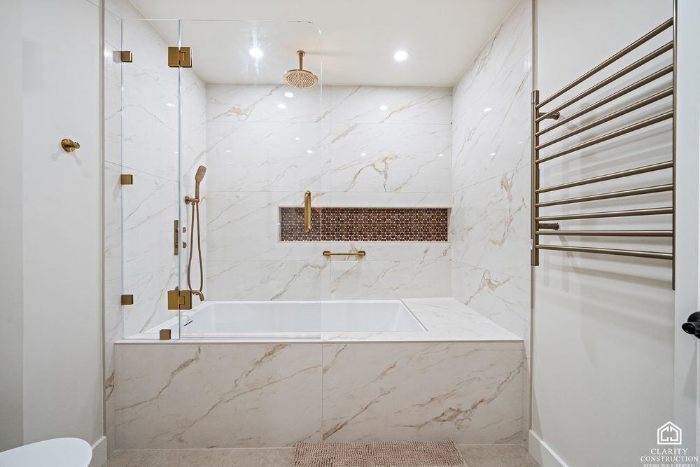 Marble tub and shower with brass fittings, a mosaic niche and a heated towel rail