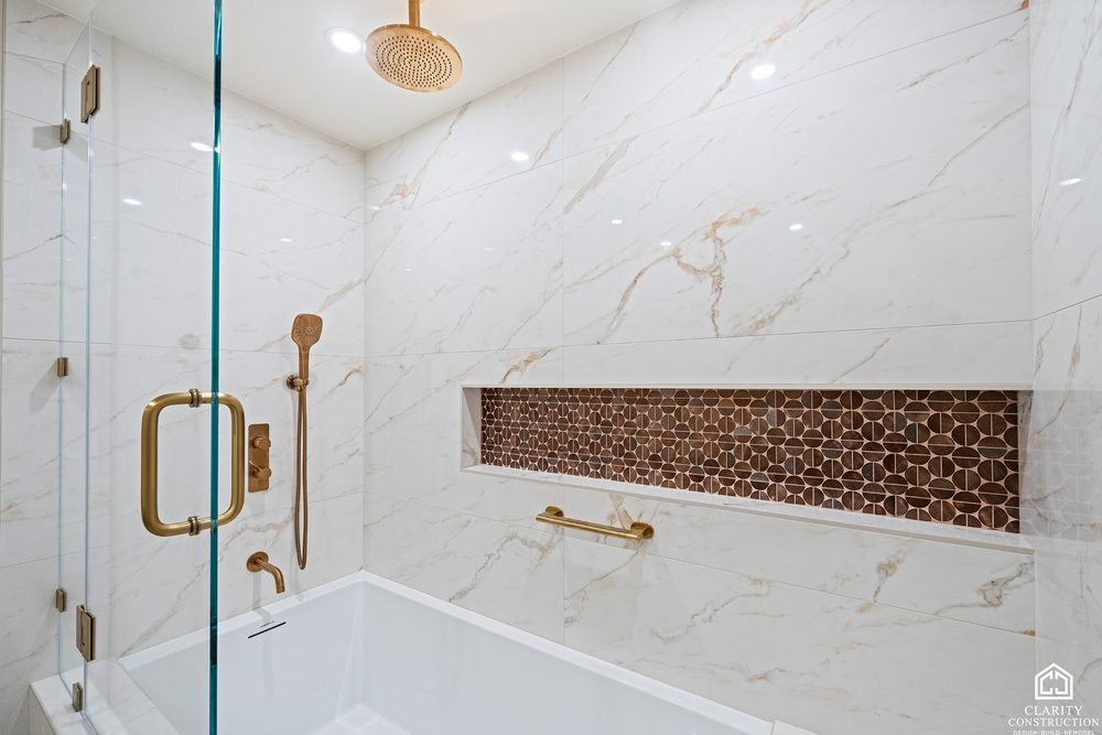 Marble shower over a tub with brass fittings, a copper mosaic niche and a rain head