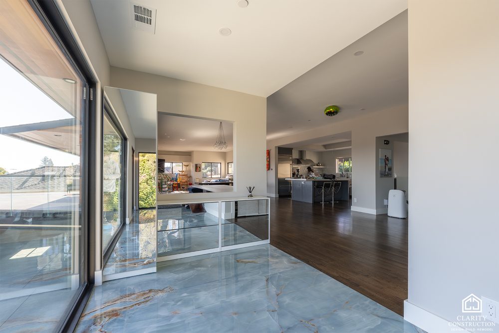 Open plan kitchen and living room with dark wood floors and a wall of glass onto the deck