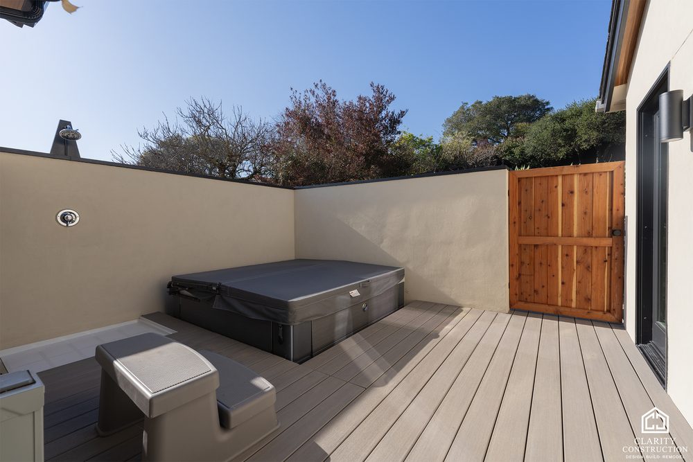 Sunken spa on a composite deck behind a rendered privacy wall