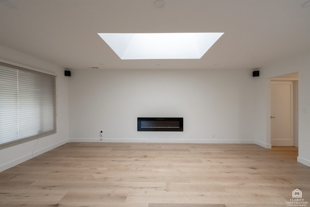 Living room with a linear fireplace, a skylight and wide-plank oak floors