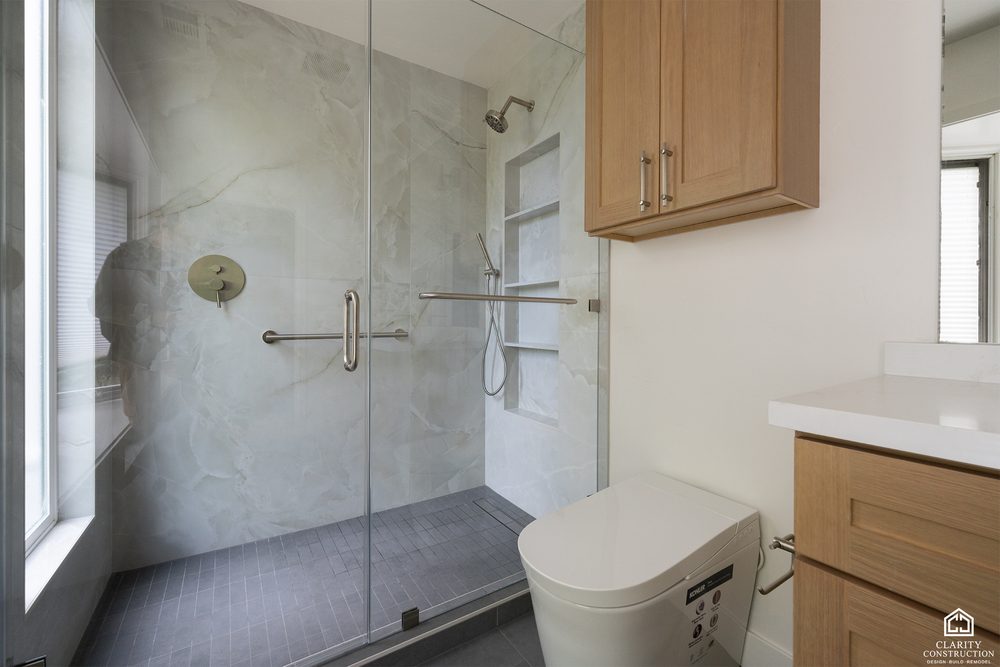 Curbless walk-in shower with large-format tile, a bench and a glass door