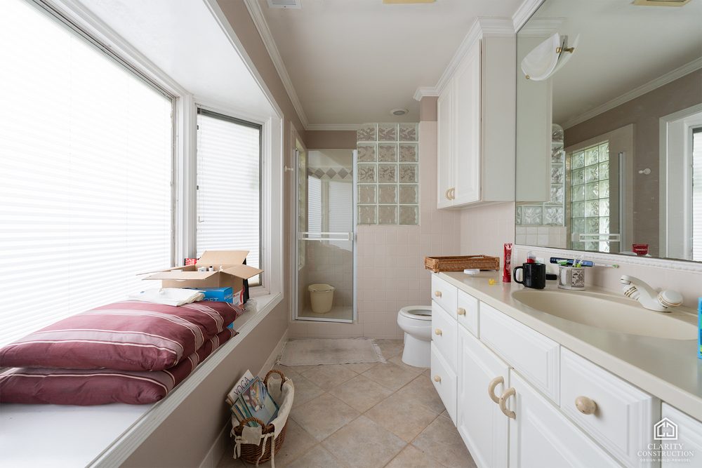 The original bathroom with a long white vanity and glass block