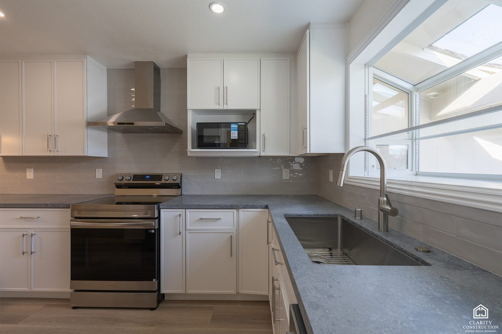 Kitchen range and hood with a skylight above and dark counters