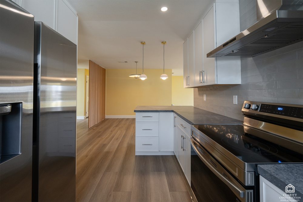 Long kitchen run with white cabinets, dark counters and stainless appliances