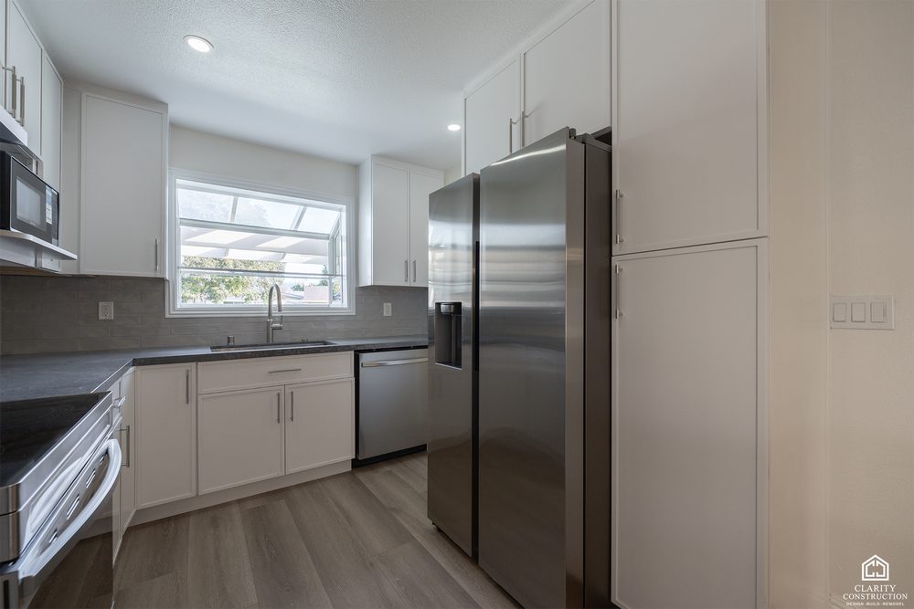 Kitchen with a stainless refrigerator, white cabinets and a window over the sink