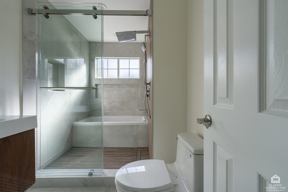 Primary bathroom with a walnut vanity, a deep tub and a glass shower