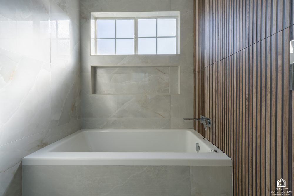 Slatted wood feature wall beside the tub in the primary bathroom