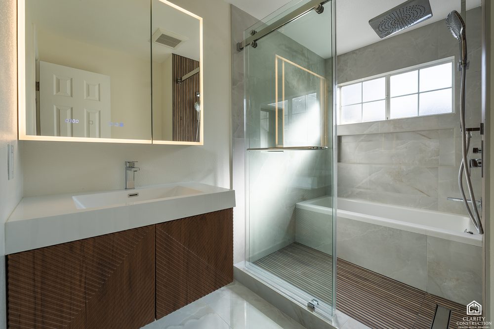 Walnut vanity with a backlit mirror and a window in the primary bathroom